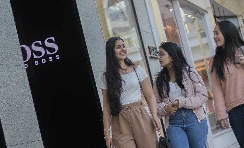 Photograph of three people walking close together in a shopping centre.