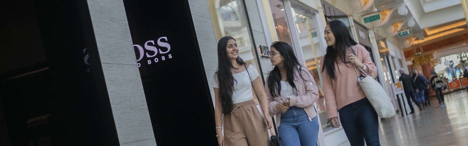 Photograph of three people walking close together in a shopping centre.