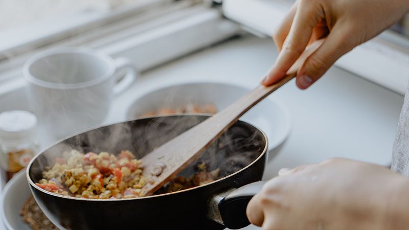 Student placing a home cooked meal from the pan to the plate