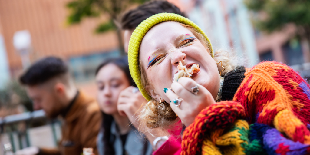 A student eating outside at a restaurant in Manchester