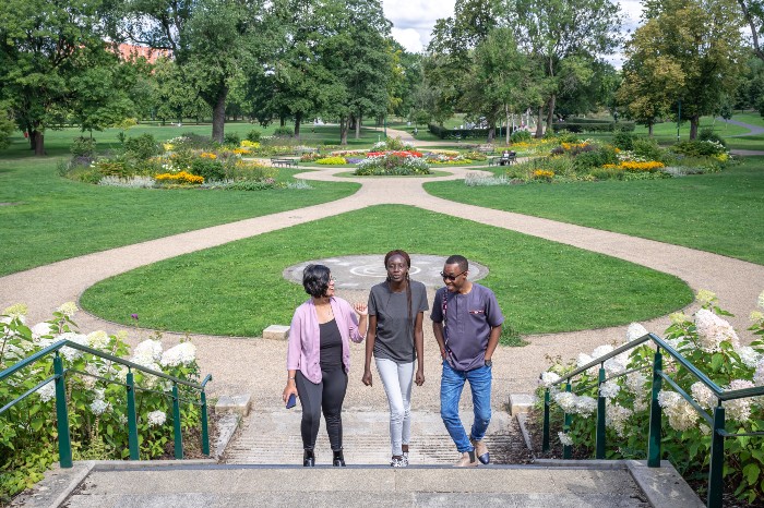 Three international students standing in Peel Park in Salford.