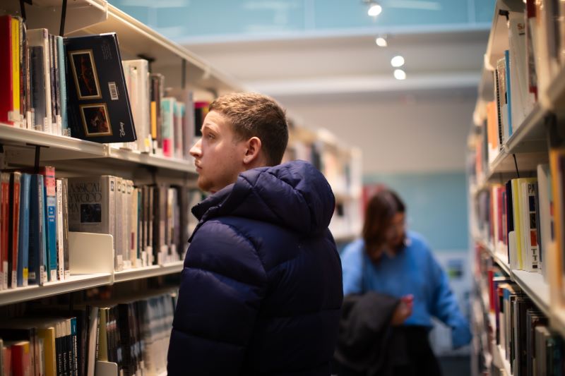 Student walking down the Library book aisle.