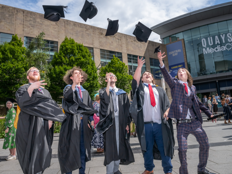 Graduates throwing their caps outside MediaCity.