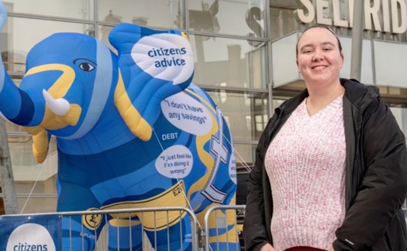 Student looking towards the camera standing in front of an inflatable elephant