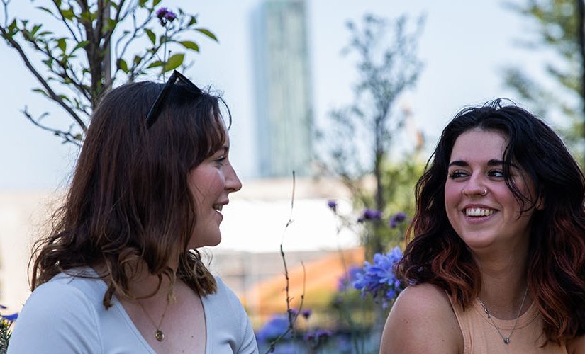 Two students talking outside in the summer sunshine.