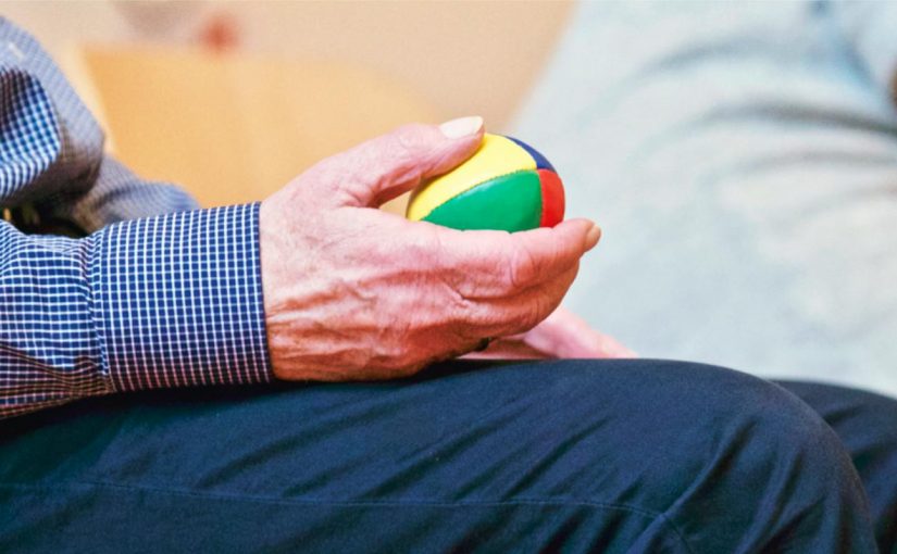 Elderly individual holding a weighted ball in one hand