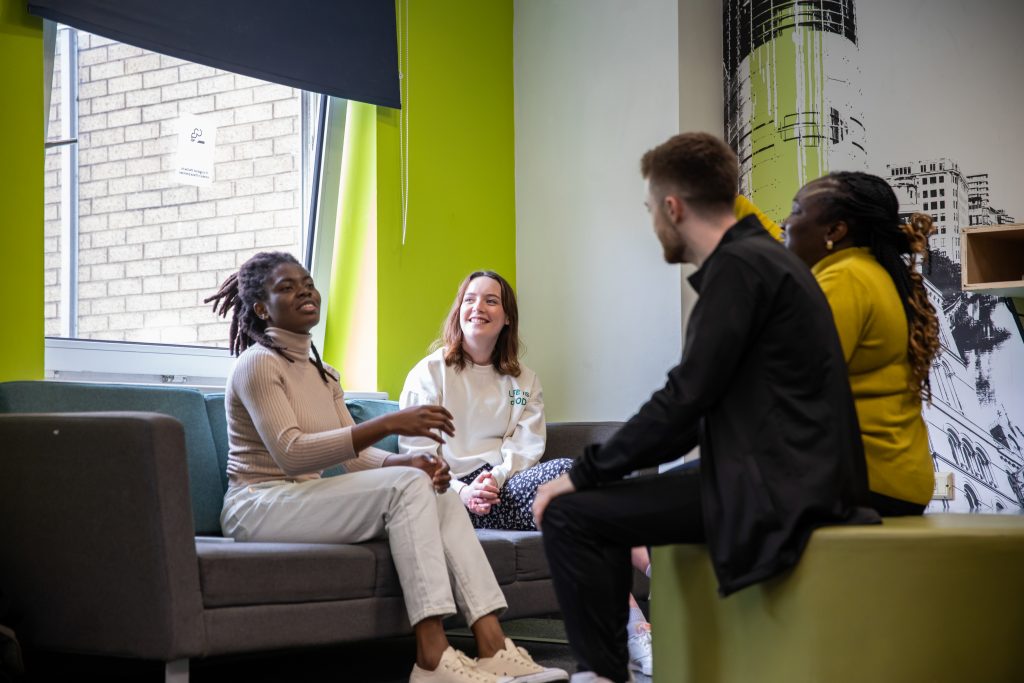 Four students are talking and laughing in student accommodation.